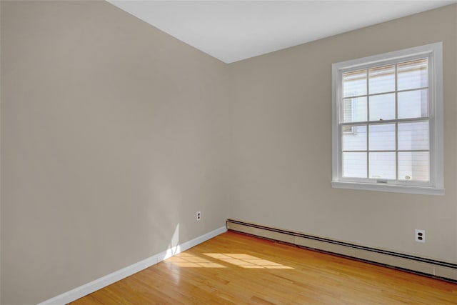 spare room featuring light wood-style floors, a baseboard radiator, and baseboards