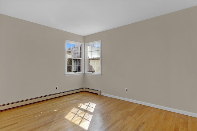 empty room featuring a baseboard heating unit, light wood-style flooring, and baseboards