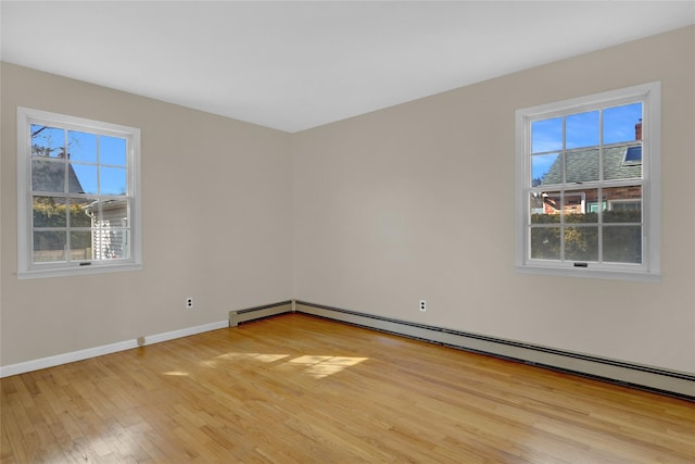 spare room with baseboards, a baseboard heating unit, and light wood-style floors