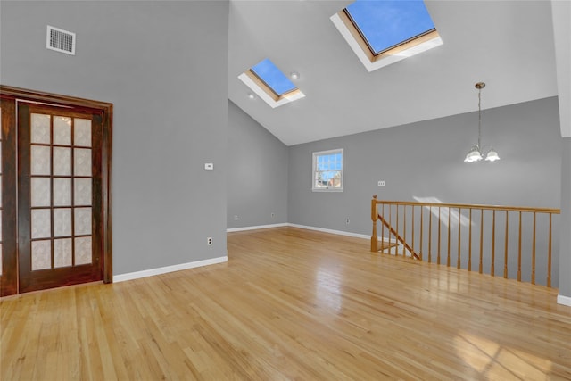 unfurnished room featuring high vaulted ceiling, visible vents, light wood-style flooring, a chandelier, and baseboards