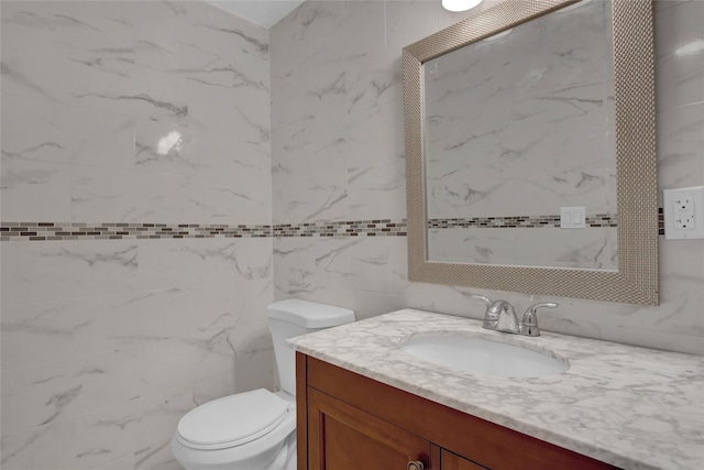 half bathroom with tile walls, vanity, and toilet