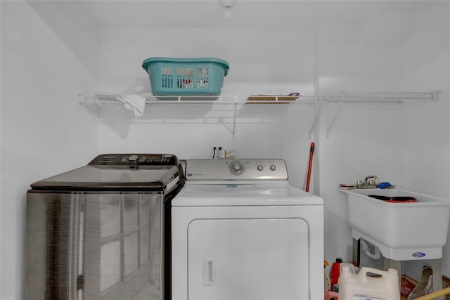 clothes washing area with laundry area, a sink, and separate washer and dryer