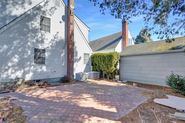 view of property exterior featuring cooling unit, a patio area, and a chimney