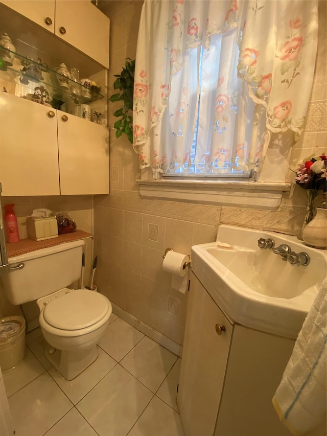 half bath featuring tile patterned flooring, tile walls, toilet, and vanity