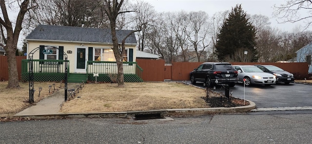 bungalow-style house featuring driveway, fence, and roof with shingles