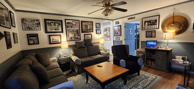 living room with ornamental molding, a ceiling fan, and wood finished floors