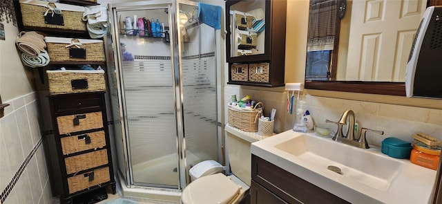 bathroom with tile walls, toilet, a shower stall, and vanity