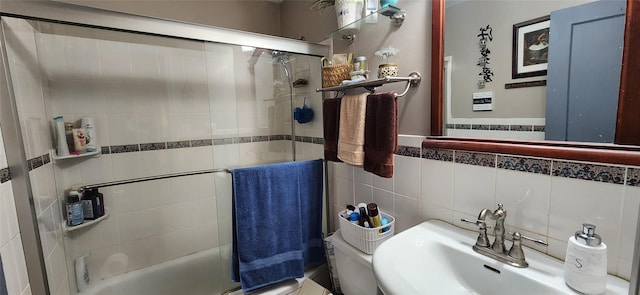 full bath featuring bath / shower combo with glass door, a sink, and tile walls