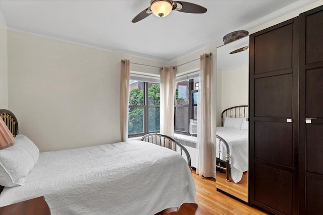 bedroom with crown molding, light wood-style flooring, and ceiling fan