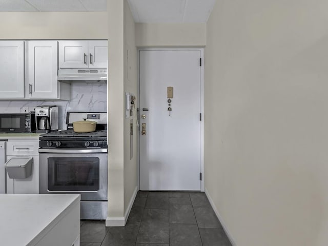 kitchen with black microwave, gas range, under cabinet range hood, white cabinetry, and backsplash