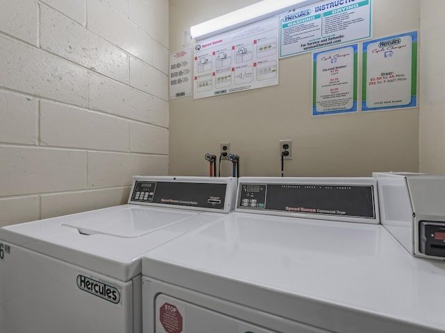 common laundry area with concrete block wall and washer and clothes dryer