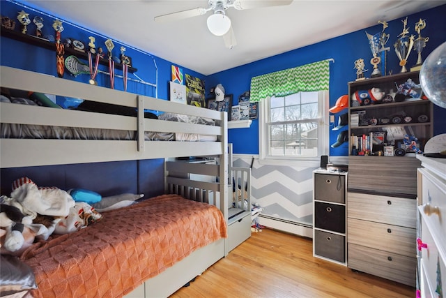 bedroom with a baseboard radiator, wood finished floors, and a ceiling fan