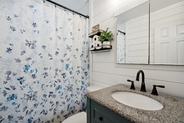 bathroom featuring toilet, wooden walls, a shower with shower curtain, and vanity