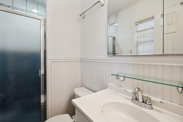 full bathroom with a wainscoted wall, vanity, a shower stall, and toilet