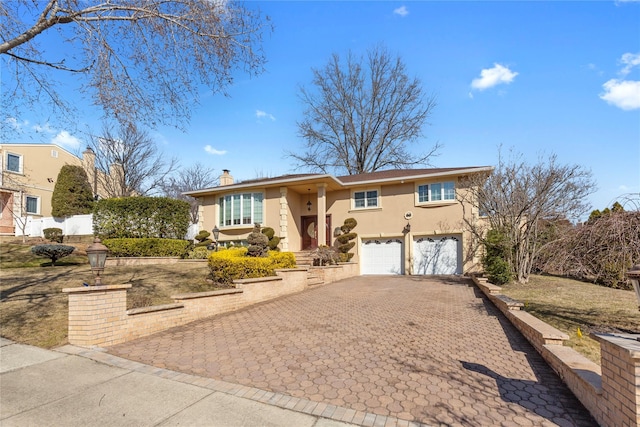 view of front of home with a garage, decorative driveway, a chimney, and stucco siding