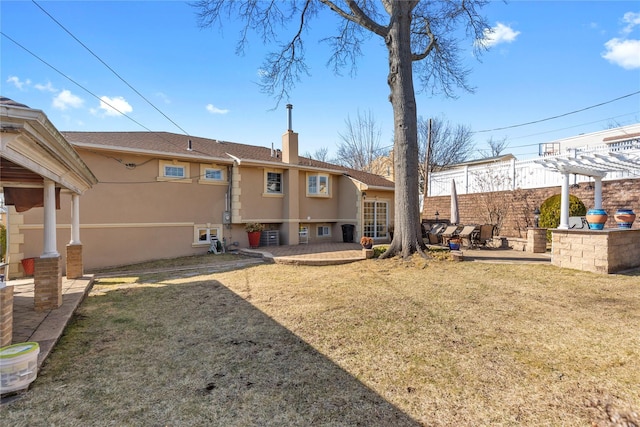 back of house with a chimney, stucco siding, a lawn, a patio area, and a pergola