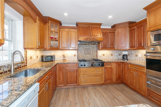 kitchen with light wood finished floors, custom range hood, stainless steel appliances, a sink, and a warming drawer