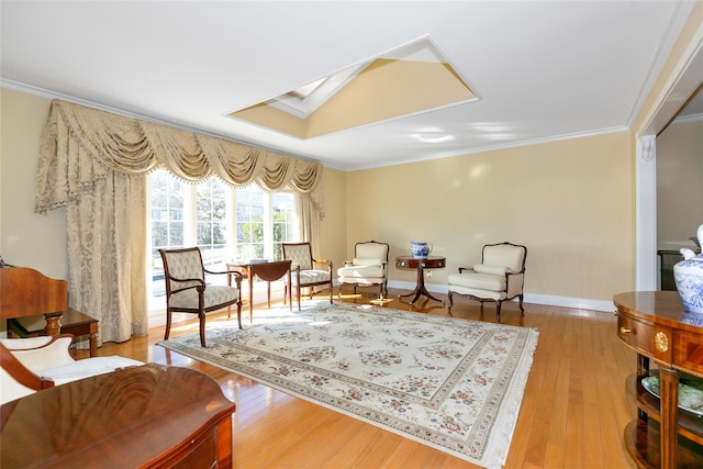 living area with ornamental molding, wood-type flooring, a skylight, and baseboards