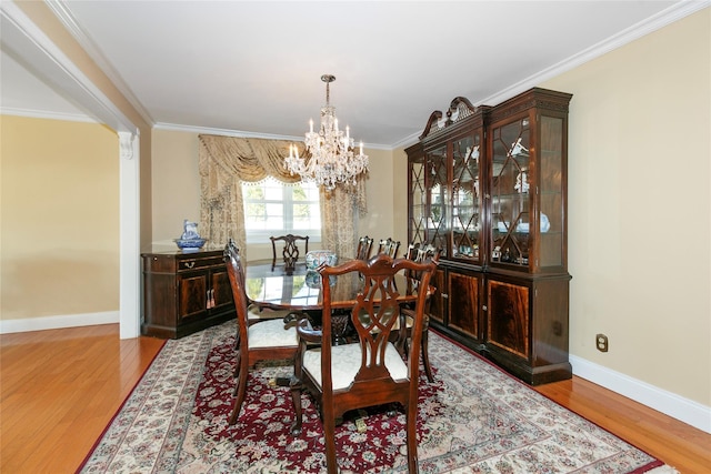 dining room with ornamental molding, wood finished floors, and baseboards