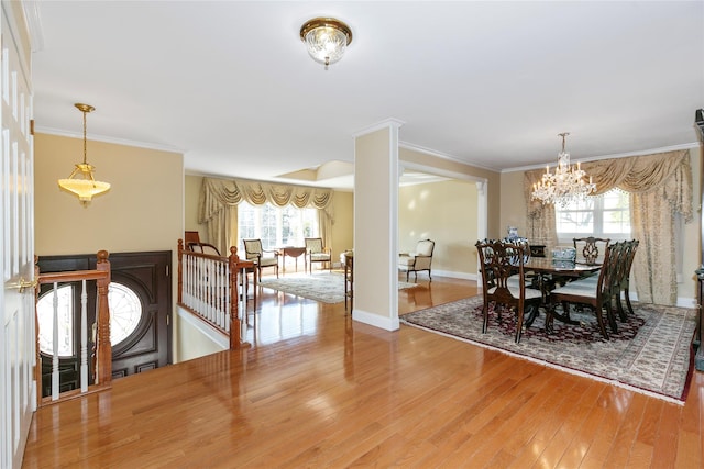 dining area featuring baseboards, ornamental molding, wood finished floors, and a notable chandelier