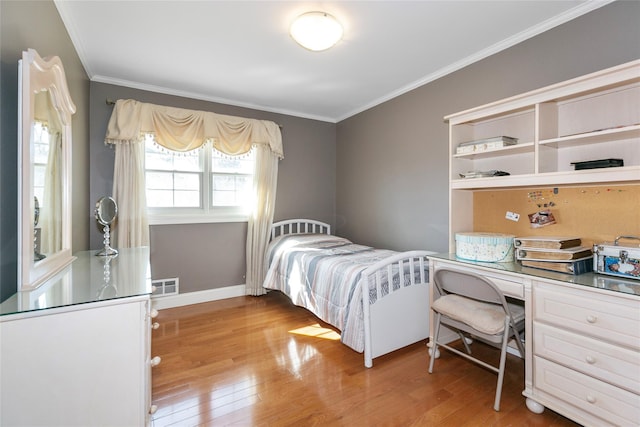 bedroom with baseboards, light wood finished floors, visible vents, and crown molding