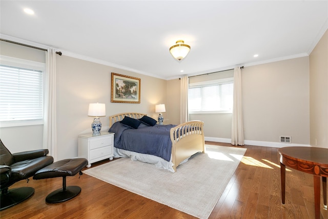 bedroom with visible vents, baseboards, wood finished floors, crown molding, and recessed lighting