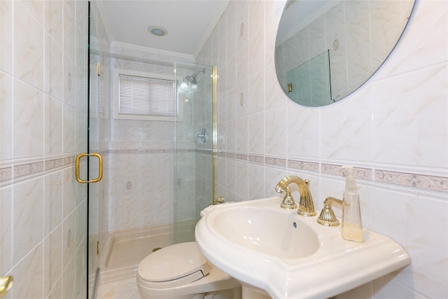 bathroom featuring a stall shower, tile walls, toilet, ornamental molding, and a sink