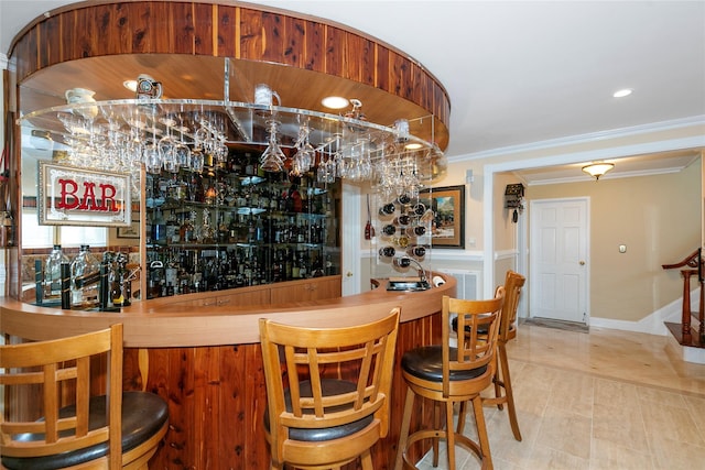 bar featuring a bar, baseboards, crown molding, and recessed lighting