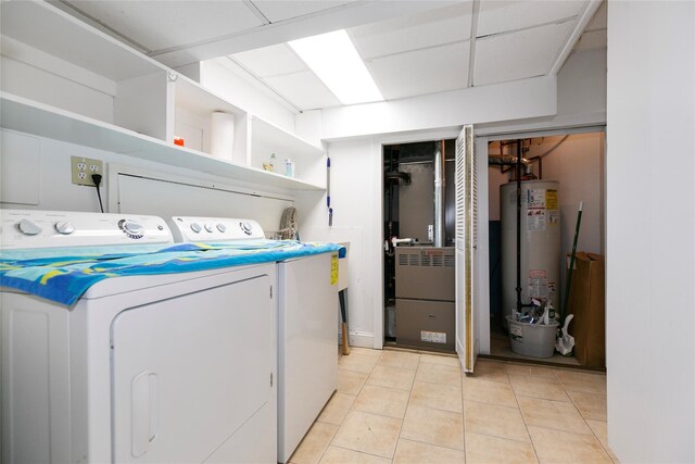 clothes washing area featuring laundry area, gas water heater, washing machine and clothes dryer, and light tile patterned flooring