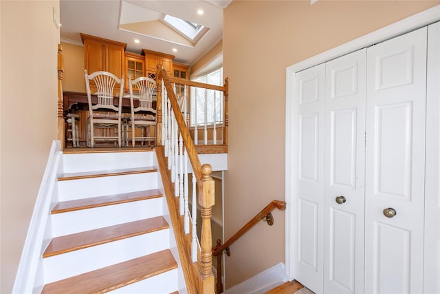 stairway with a skylight, baseboards, and recessed lighting