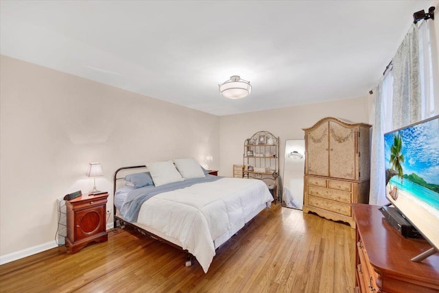 bedroom featuring light wood finished floors and baseboards