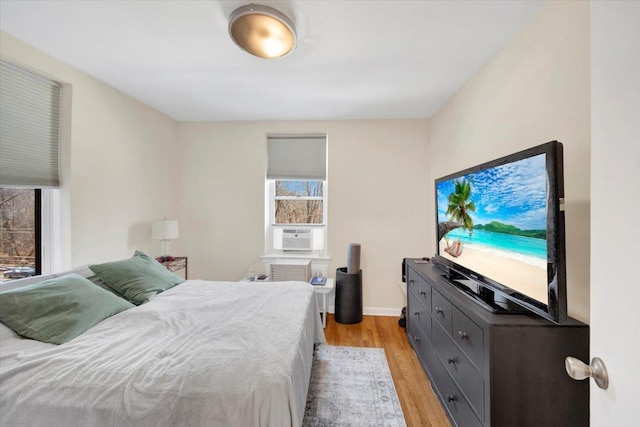 bedroom featuring light wood finished floors, baseboards, and cooling unit