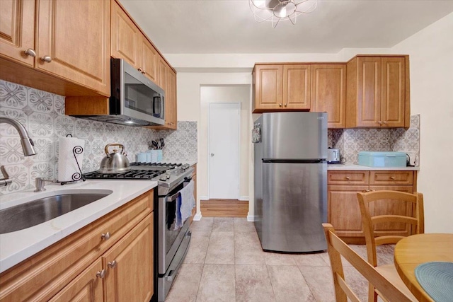 kitchen with light countertops, backsplash, appliances with stainless steel finishes, light tile patterned flooring, and a sink