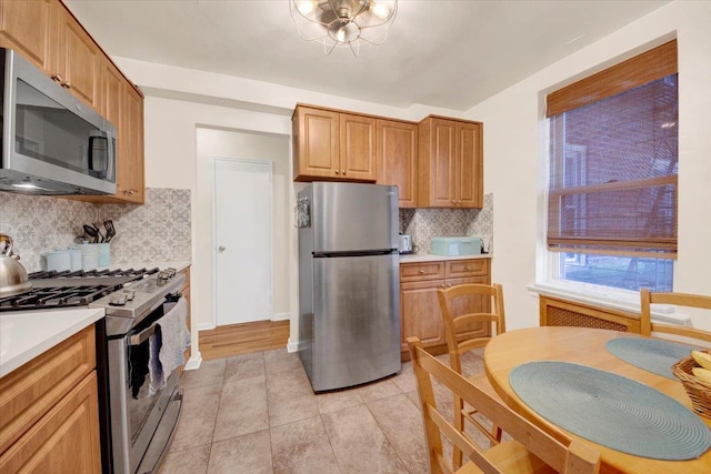 kitchen featuring light tile patterned floors, light countertops, appliances with stainless steel finishes, decorative backsplash, and brown cabinetry