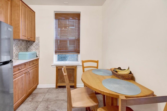 dining room with radiator heating unit, baseboards, and light tile patterned flooring