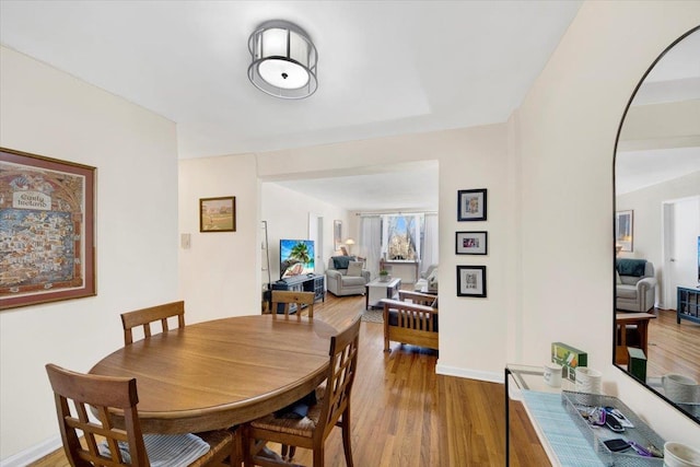 dining space with arched walkways, wood finished floors, and baseboards