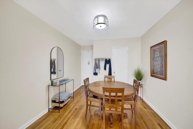 dining space featuring light wood-type flooring and baseboards