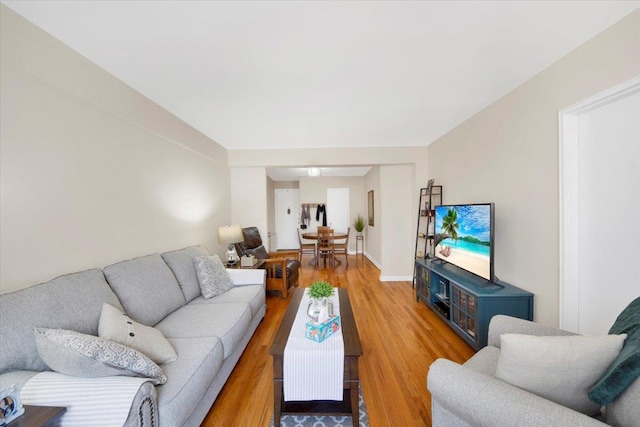 living area featuring baseboards and light wood finished floors