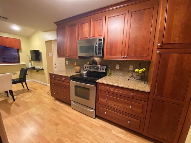 kitchen featuring tasteful backsplash, baseboards, light wood-style flooring, appliances with stainless steel finishes, and light stone counters