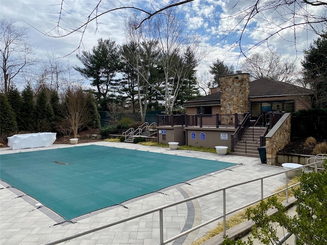 community pool featuring stairs, a patio, and a wooden deck