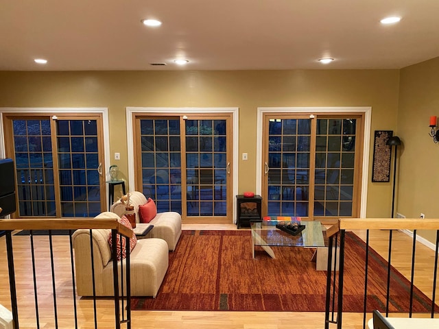 living area featuring a wood stove, visible vents, wood finished floors, and recessed lighting