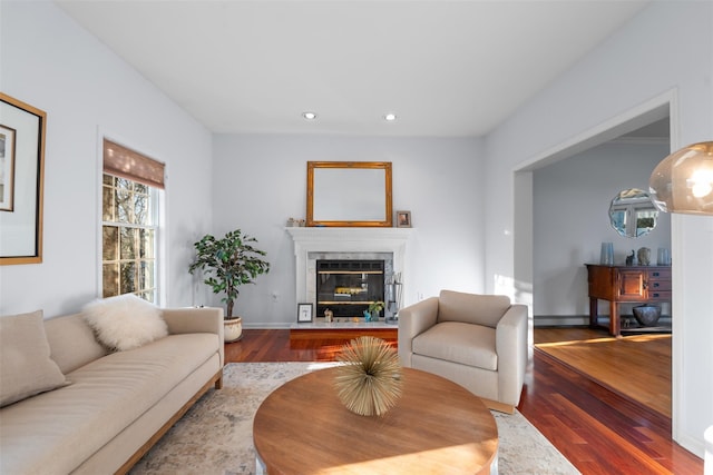 living area with a glass covered fireplace, baseboards, recessed lighting, and wood finished floors