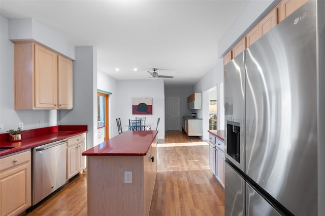 kitchen featuring stainless steel appliances, dark countertops, a center island, and light wood-style floors