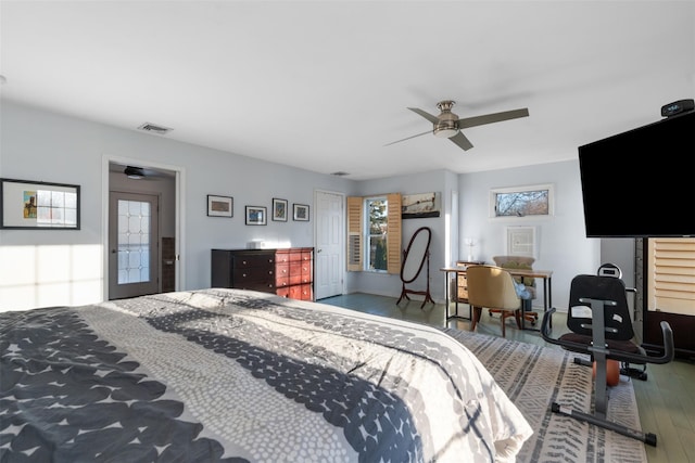 bedroom featuring a ceiling fan, visible vents, and wood finished floors