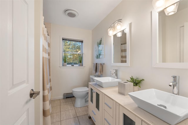 bathroom featuring toilet, double vanity, baseboard heating, and a sink