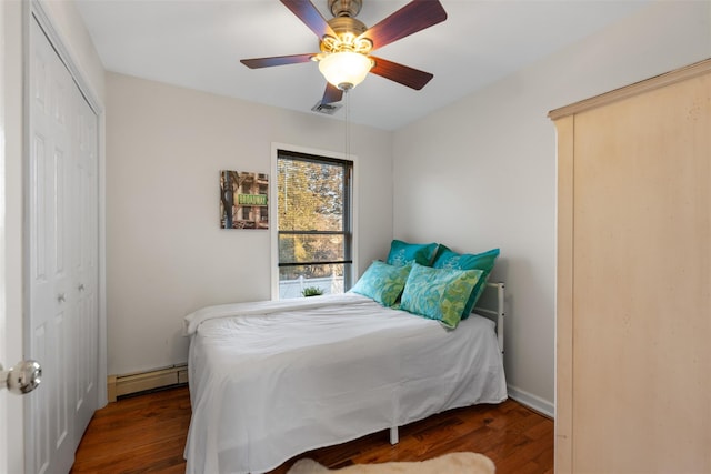 bedroom with visible vents, a baseboard radiator, ceiling fan, wood finished floors, and a closet