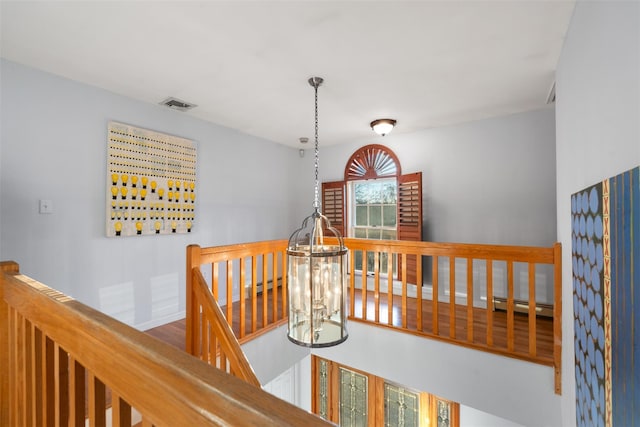 hall with visible vents, baseboards, a baseboard radiator, wood finished floors, and an upstairs landing