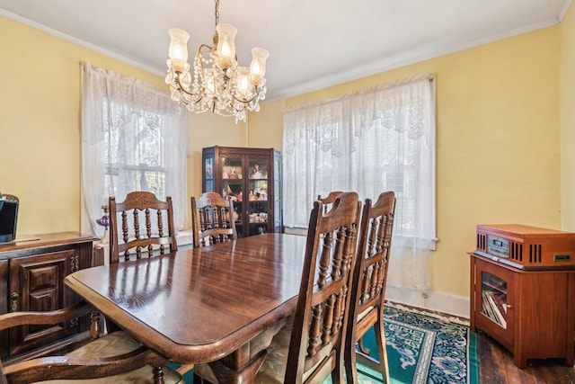 dining room with a chandelier, baseboards, wood finished floors, and crown molding