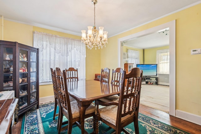 dining room featuring baseboards, a chandelier, wood finished floors, and ornamental molding