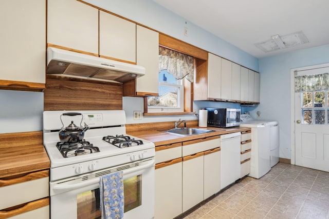 kitchen featuring under cabinet range hood, white appliances, wood counters, a sink, and washer / dryer